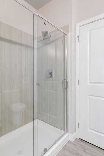 A white door is next to a glass shower stall.